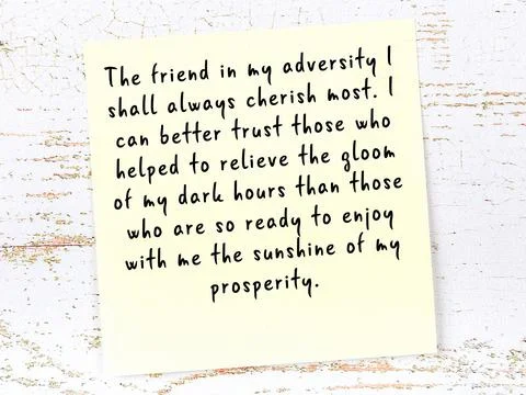 Yellow sticky note with smart quotation handwritten on it hanging on wooden w Фото