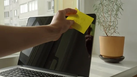 Yellow sticky note with "Stay Safe" text being sticked to laptop display Stock Footage 127656298