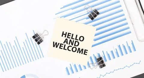 Yellow sticky notes with text HELLO AND WELCOME on the white office desk. B.. Stock Photos