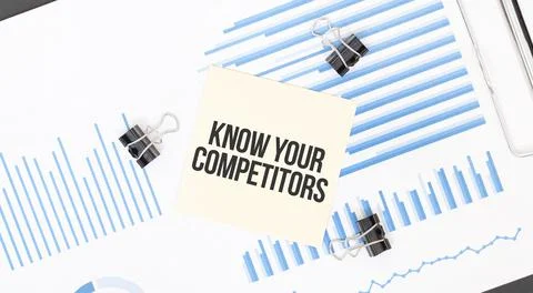 Yellow sticky notes with text KNOW YOUR COMPETITORS on the white office desk. Stock Photos