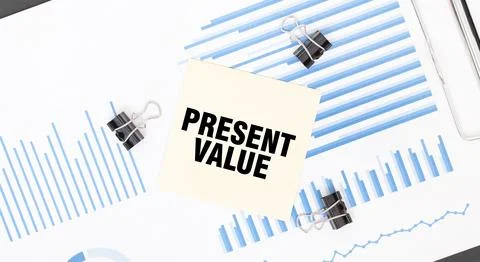 Yellow sticky notes with text PRESENT VALUE on the white office desk. Busin.. Stock Photos