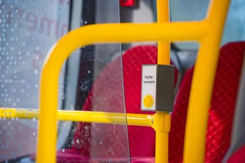 Yellow stop request button on public bus with red seats and rain droplets o.. Photos