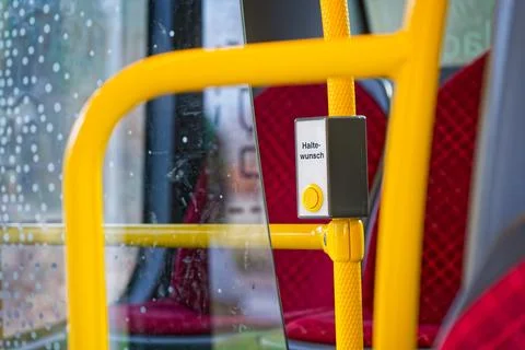 Yellow stop request button on public bus with red seats and rainy window Stock Photos