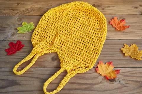 Yellow string bag on a wooden background with autumn leaves around. Zero waste Stock Photos