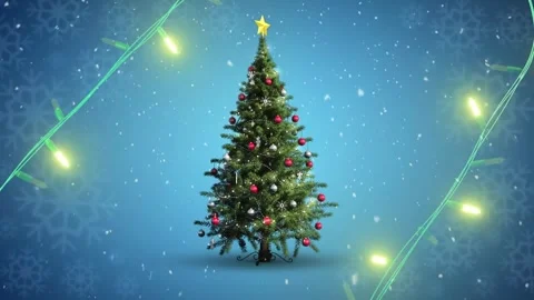 Yellow string lights flashing over decorated christmas tree and falling snow on Stock Footage 253158727
