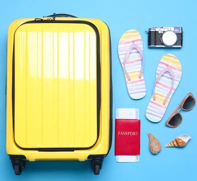 Yellow suitcase and beach objects on blue background, flat lay Fotos de archivo