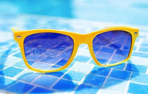 Yellow sunglasses on a background of a pool. Stock Photos
