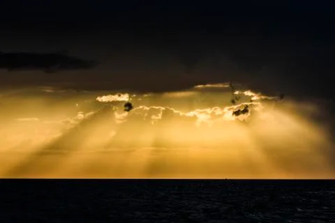 Yellow sunset with piercing light rays through the clouds. Stock Photos
