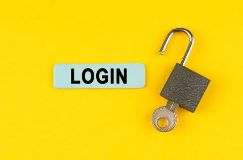 On the yellow surface lies an open lock with a key, next to it is a sticker.. Stock Photos