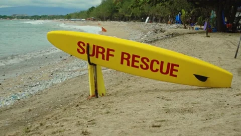 Yellow surfboard on beach with red text surf rescue emergency on a beach Stock Footage 146459161