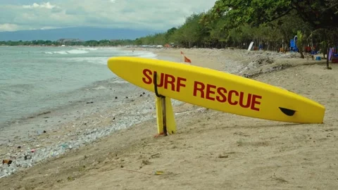 Yellow surfboard on beach with red text surf rescue emergency on a beach Stock Footage 146459518