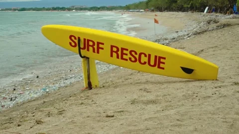 Yellow surfboard on beach with red text surf rescue emergency on a beach Stock Footage 146459963