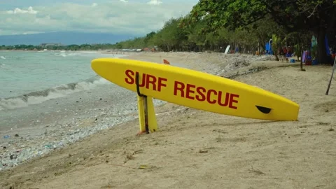 Yellow surfboard on beach with red text surf rescue emergency on a beach Stock Footage 146460341