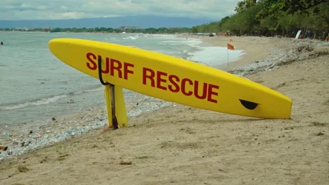 Yellow surfboard on beach with red text surf rescue emergency on a beach Stock Footage 146460661