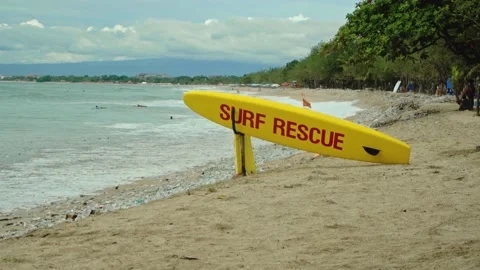 Yellow surfboard on beach with red text surf rescue emergency on a beach Stock Footage 146464061