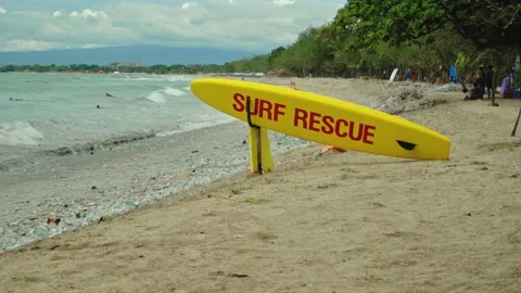 Yellow surfboard on beach with red text surf rescue emergency on a beach Stock Footage 146464344