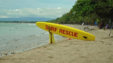 Yellow surfboard on beach with red text surf rescue emergency on a beach Stock Footage 146464551