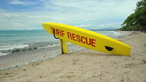 Yellow surfboard on beach with red text surf rescue emergency on a beach Stock Footage 146475660