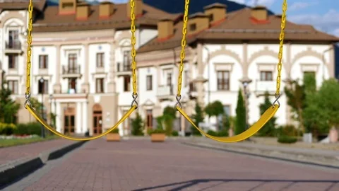 A yellow swing on steel chains pumps the wind on the playground. Slow motion. Stock Footage