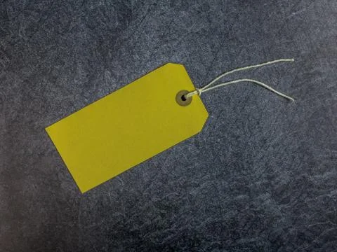 Yellow tag with string on a dark slate background Stock Photos