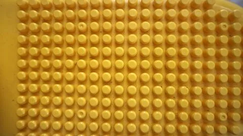 Yellow textured surface creating a repetitive pattern with plastic studs pr.. Stock Photos