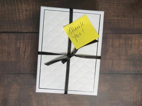Yellow Thank You Post-it Note on gift box with black ribbon on a wood backg.. Stock Photos