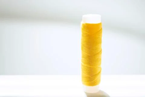 Yellow thread spool on a white bright table. Stock Photos