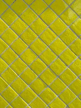 Yellow tiled wall pattern with textured glazed surface Stock Photos