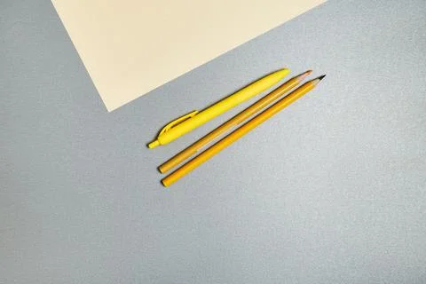 Yellow tools for writing exhausting next to a piece of paper on a gray surfac 스톡 사진