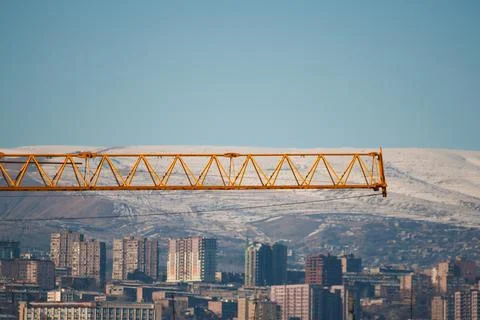 Yellow tower crane against the backdrop of the city from a close distance, the Stock Photos