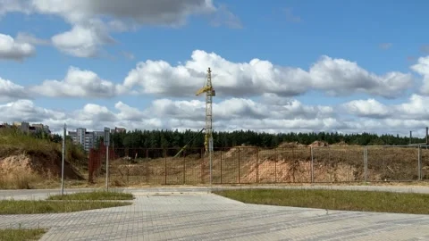 Yellow tower crane behind rusty metal fence at construction site Vídeo Stock 344041539