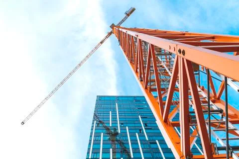 Yellow tower crane. Bottom view of a tall construction crane next to a modern Stock Photos