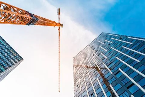 Yellow tower crane. Bottom view of a tall construction crane next to a modern Stock Photos