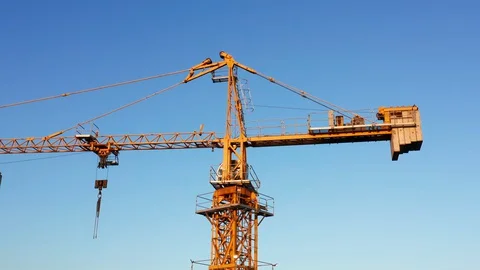 Yellow tower crane on a construction site, against clear blue sky. Video stock 128160541