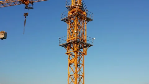 Yellow tower crane on a construction site, against clear blue sky Stock Footage 128169318