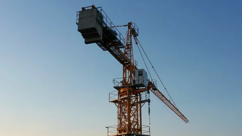 Yellow tower crane on a construction site, against clear blue sky Stock Footage 128188326