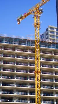 Yellow tower crane at construction site of multi story building Stock Photos