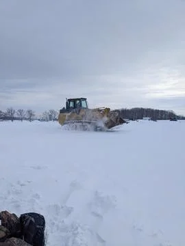 Yellow tracked loader driving through deep snow in a winter rural field Fotos Stock