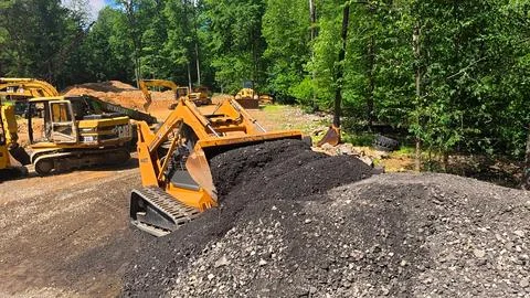 Yellow Tracked Skid Steer Loader Working On Soil And Gravel Pile Stock Photos