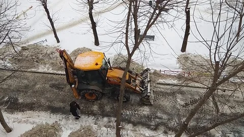 Yellow tractor cleans the road from the snow in a residential area of the city Stock Footage 104130400