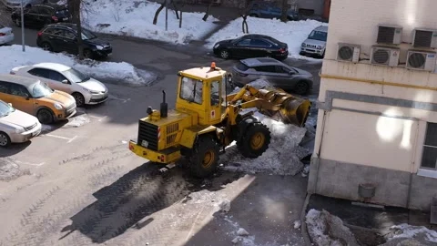 Yellow tractor clears snow from a yard. Stock Footage 327902544
