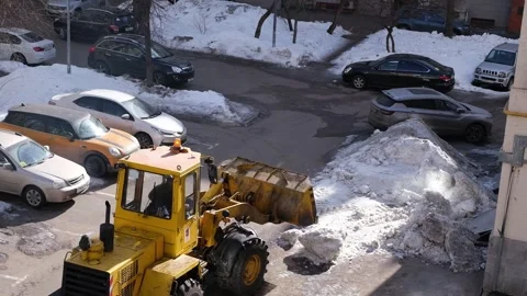 Yellow tractor clears snow from a yard. Stock Footage 332846165