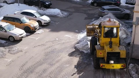 Yellow tractor clears snow from a yard. Stock Footage 332846170