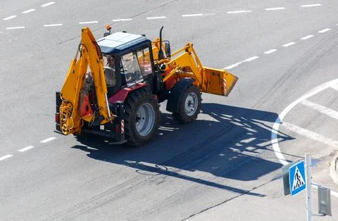 A yellow tractor is driving down a road Foto stock