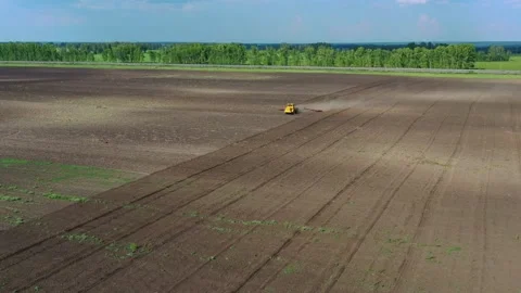 A yellow tractor with a red plow plows the soil. Stock Footage 139855504