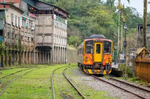The yellow train is parked by the station platform. A small station on the hill. Stock Photos