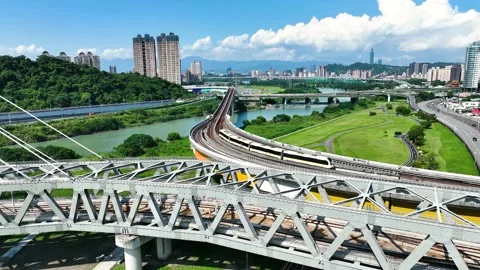 Yellow train passing bridge in beautiful riverside and green area Stock Footage 218347699