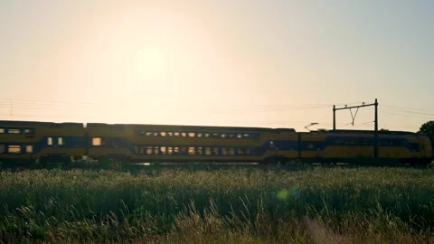 Yellow train passing through countryside at sunset Stock Footage 314071315