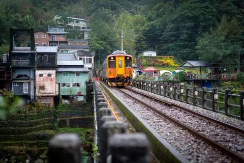 The yellow train is passing through a small village in the valley. Stock Photos