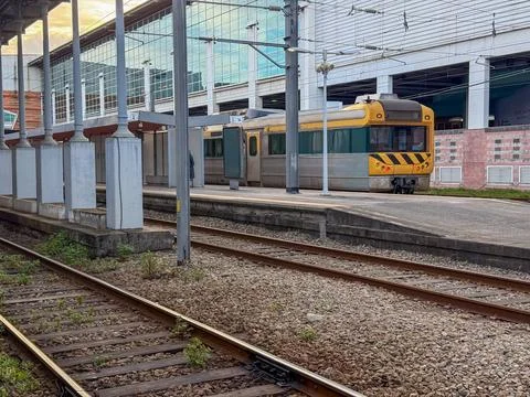 Yellow train at station platform with tracks, urban transport hub, concept of Stock Photos